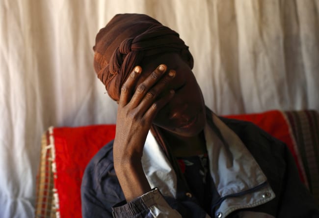 An HIV patient places her hand on her forehead during a visit by a caregiver at her home, in Lusaka, Zambia, on April 17, 2012.
