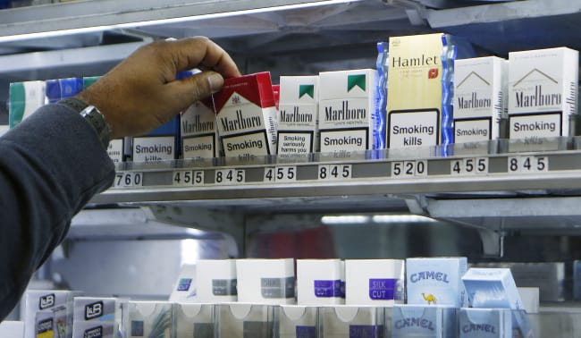 A shopkeeper reaches for a packet of cigarettes, in London, England, on November 28, 2013.