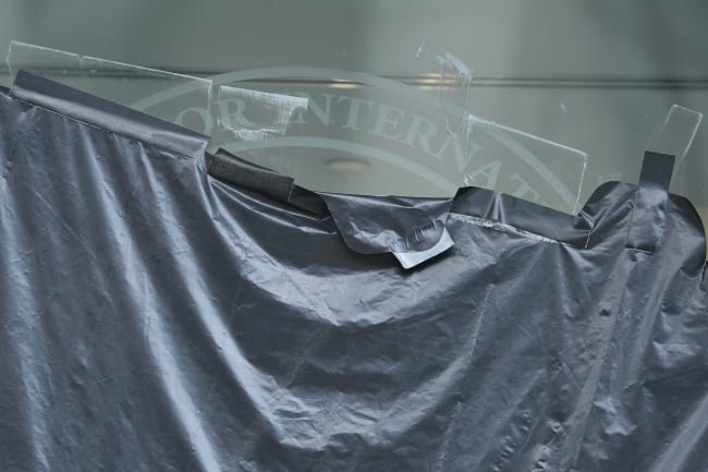 Plastic peels back to reveal the covered logo on the windows of the shuttered offices of the U.S. Agency for International Development, in Washington, DC, on July 22, 2025.