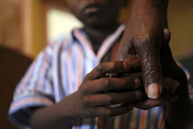 A boy holds his grandmother's hand after taking his medication at Nkosi's Haven, which provides residential care for low-income HIV-positive mothers and their children, in Johannesburg, South Africa, on November 28, 2014.