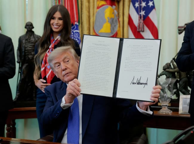 U.S. President Donald Trump displays a signed executive order regarding vaccine flexibility, in the Oval Office at the White House, in Washington, DC, on August 10, 2026.