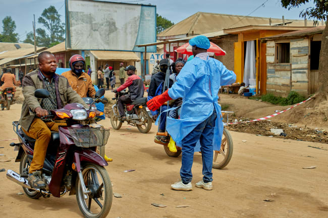 John Macki, a public health expert, controls motorcycle taxis before a health check point screening along the street, in Mongbwalu, Djugu Territory of Ituri province, Democratic Republic of the Congo, on May 23, 2026.