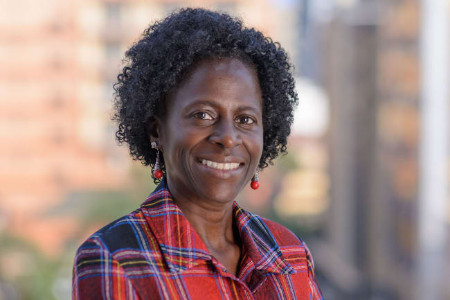 Picture shows Olive Kobusingye, Executive Director, Injury Control Center at Makerere Medical School in Kampala, Uganda. She is looking at the camera against a bright, blurred out background wearing a red-and-blue shirt in this posed shot.