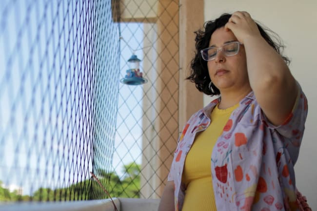 Leticia de Souza Soares, who suffers from pain and health problems caused by long COVID-19, stands on the balcony of her home, in Salvador, Brazil, on December 8, 2023.