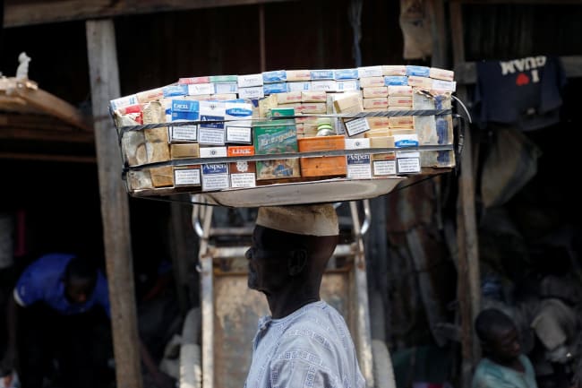 A man selling packets of cigarettes walks through a street, in the old district of Kano, Nigeria, on August 24, 2017.