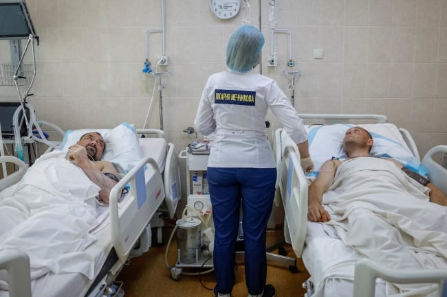 A nurse at the Mechnikov Hospital treats service members Viktor Cherniy, 52, and Vitalii Yunatskyi, 40, who were wounded during fighting against Russian forces, in an intensive care unit, in Dnipro, Ukraine, on May 14, 2025.