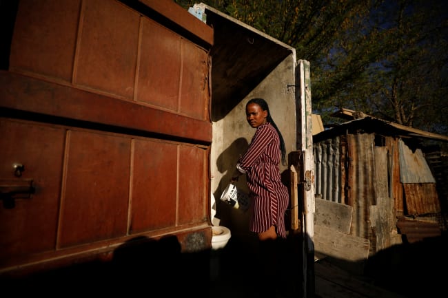 A woman pours a pot of recycled grey water into a toilet in drought-stricken Graaff-Reinet, South Africa, on November 16, 2019.