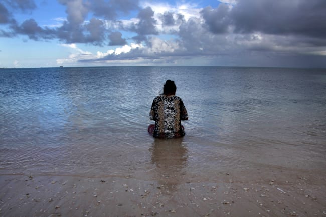 Binata Pinata scales a fish her husband caught, as she sits in the sea just off Bikeman islet, located off South Tarawa, in the central Pacific island nation of Kiribati, on May 25, 2013.