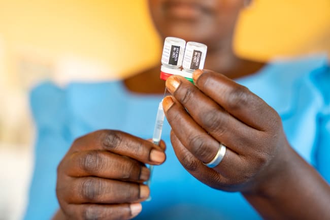 A worker holds a malaria vaccine vial to administer to a child, at Chileka Health Center, in Lilongwe, Malawi.