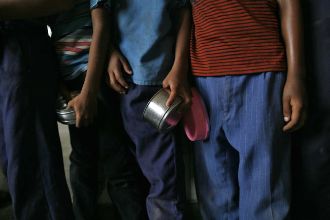 School boys carry their tiffin boxes as they wait to receive their free mid-day meal, distributed by a government-run primary school, in New Delhi, India, on July 19, 2013.