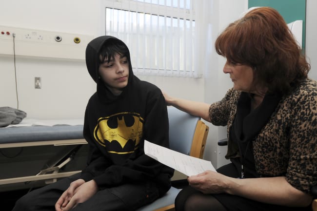 School Nurse Carolyn Rees talks to Kieran Elford, aged 13, about the MMR vaccine at the pediatric outpatients department at Morriston Hospital, in Swansea, south Wales, on April 6, 2013.