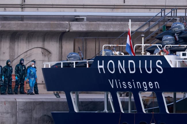 People in hazmat suits and PPE stand near the cruise ship MV Hondius, affected by a hantavirus outbreak, after it docked at the port of Granadilla de Abona, Tenerife, Spain May 11, 2026. REUTERS/Borja Suarez
