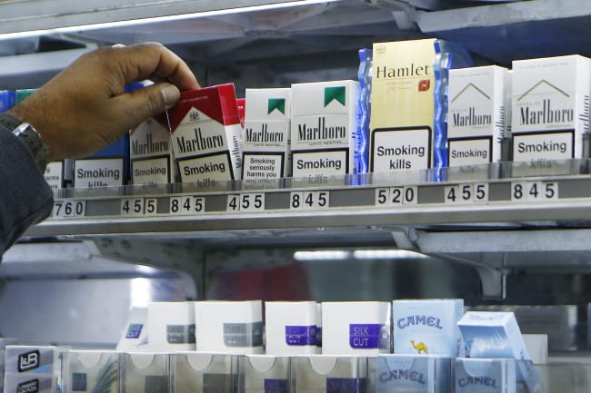 A shopkeeper reaches for a packet of cigarettes, in London, England, on November 28, 2013.