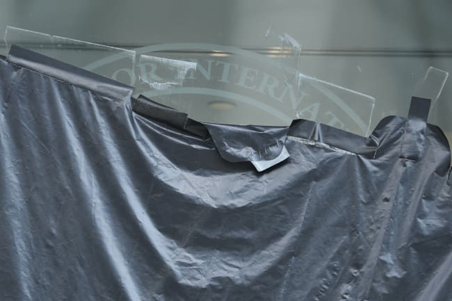 Plastic peels back to reveal the covered logo on the windows of the shuttered offices of the U.S. Agency for International Development, in Washington, DC, on July 22, 2025.