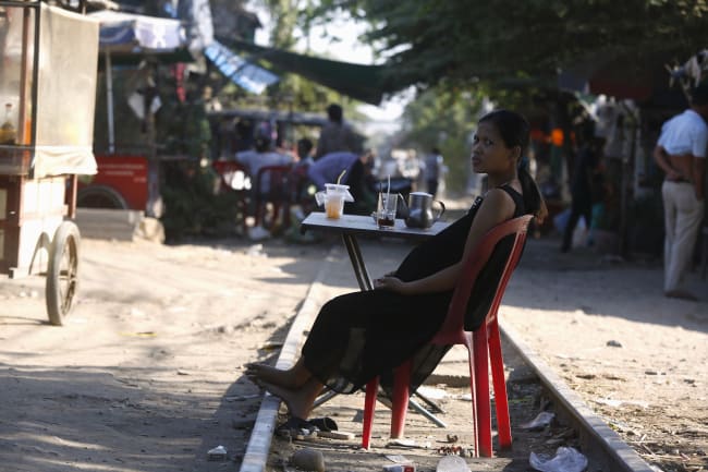 A pregnant woman rests on the railway track in front of her home, in Phnom Penh, Cambodia, on February 4, 2016.