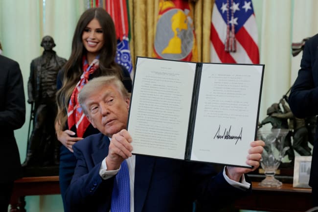 U.S. President Donald Trump displays a signed executive order regarding vaccine flexibility, in the Oval Office at the White House, in Washington, DC, on August 10, 2026.