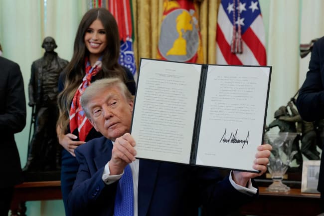 U.S. President Donald Trump displays a signed executive order regarding vaccine flexibility, in the Oval Office at the White House, in Washington, DC, on August 10, 2026.