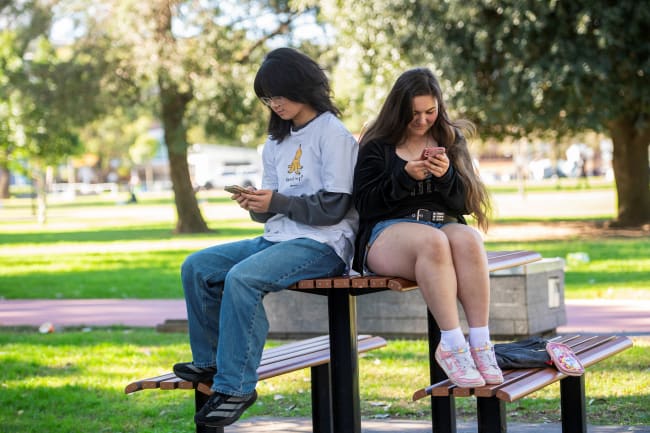 Annie Wang, 15, and Novva Tolson, 15, pose as they scroll through their social media feeds, in Sydney, Australia, on July 14, 2026.