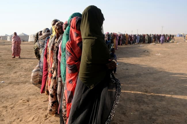 Displaced women stand in a long queue to receive food supplies at a displacement camp, in Al-Dabbah, Sudan, on November 13, 2025.