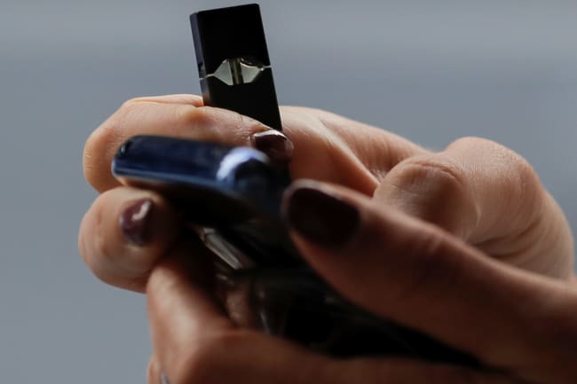 A woman holds a Juul e-cigarette while walking, in New York, on September 27, 2018.