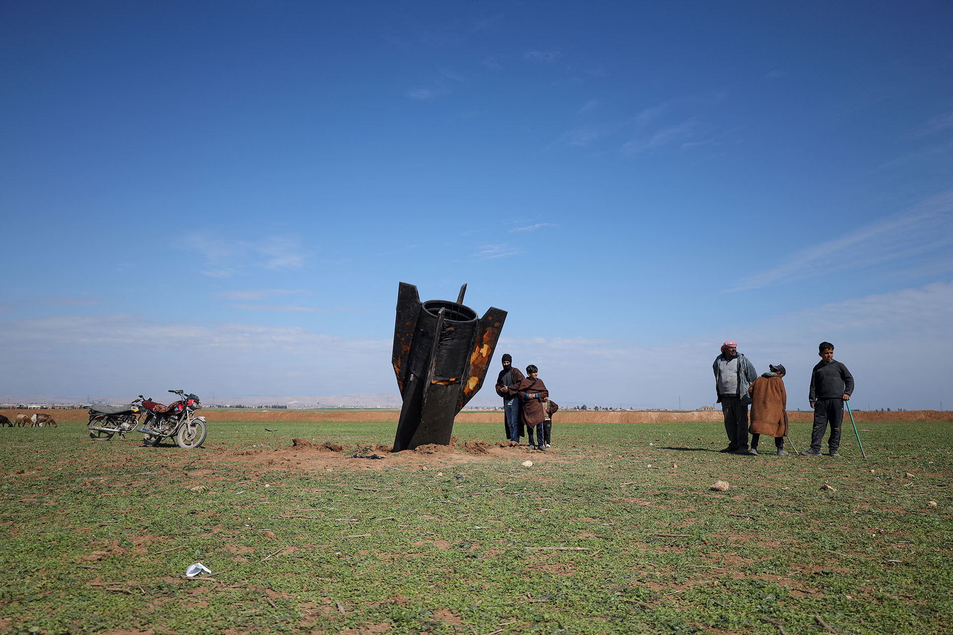 People stand next to an Iranian missile after it fell near Qamishli International Airport, near the Turkish border in the Qamishli district of Hasakah, Syria, on March 4, 2026, amid the U.S.-Israeli conflict with Iran.