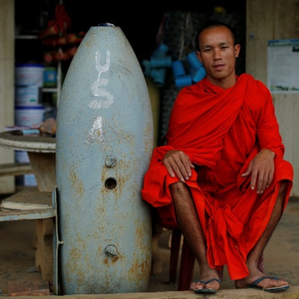 <p>A Buddhist monk poses next to unexploded bombs dropped by the U.S. Air Force planes during the Vietnam War, in Xieng Khouang in Laos September 3, 2016. </p>
