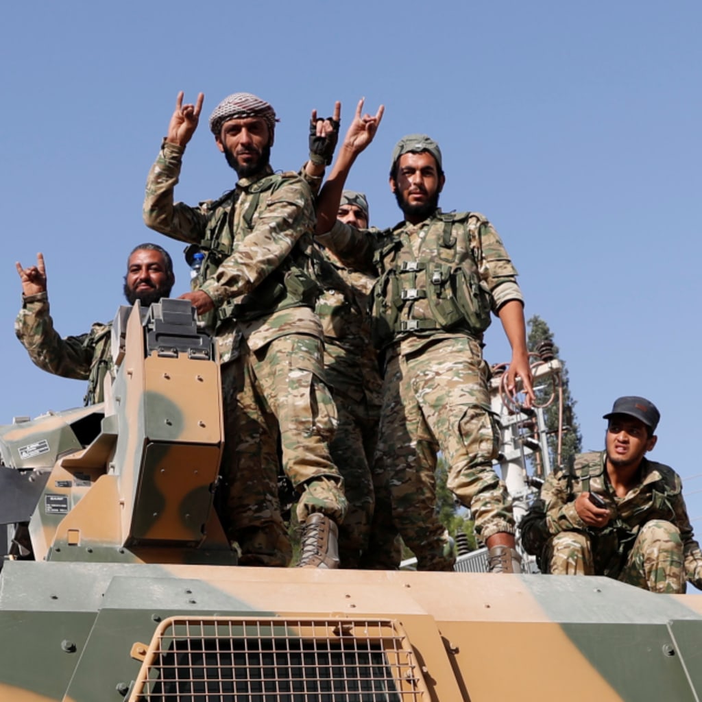 <p>Members of the Syrian National Army on top of an armored vehicle in Ceylanpinar, Turkey.</p>