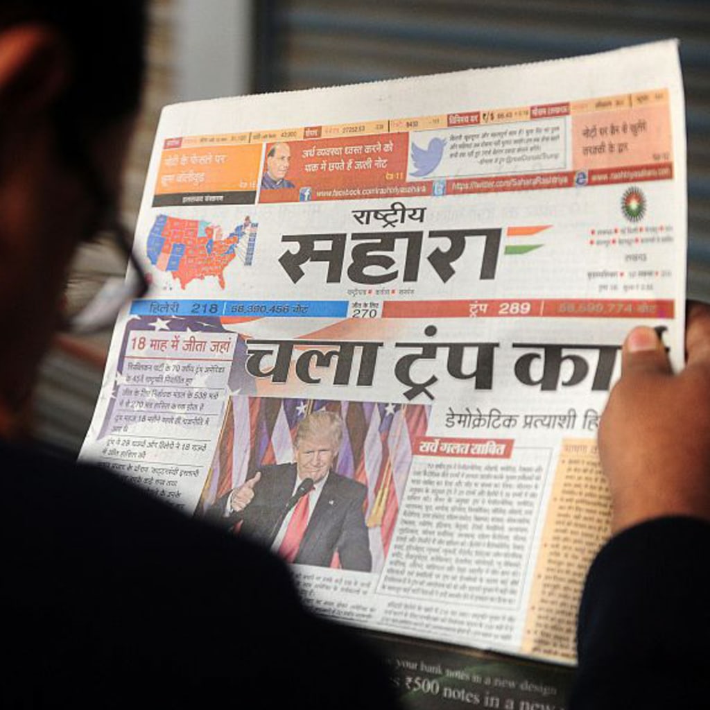<p>An Indian man reads a newspaper article about newly elected U.S. President Donald J. Trump, on a street in Allahabad. </p>