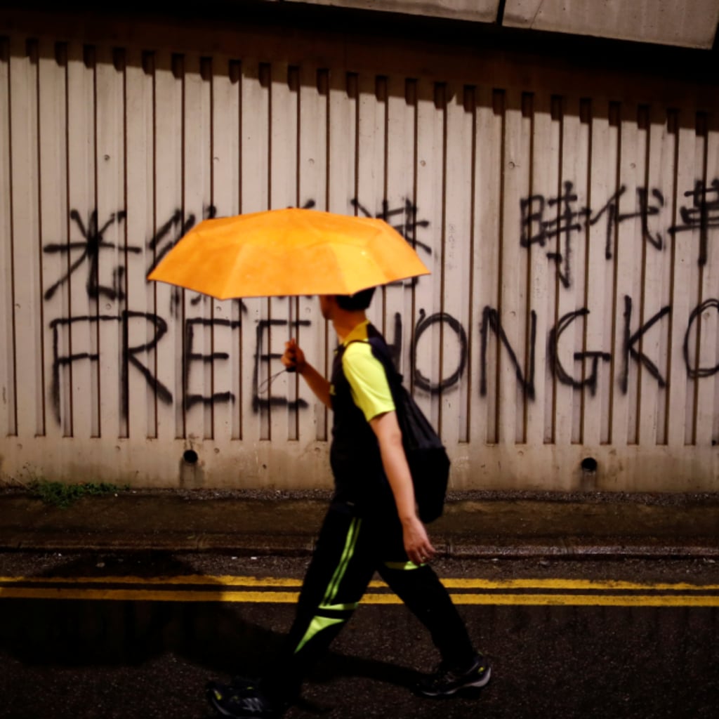 <p>A man walks past a graffiti during a march to demand democracy and political reforms in Hong Kong, China, August 18, 2019.</p>
