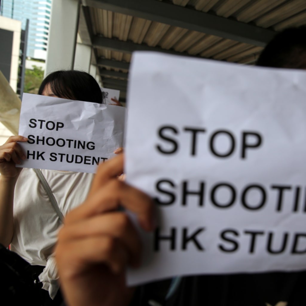 <p>Protesters hold signs following a day of violence in Hong Kong.</p>
