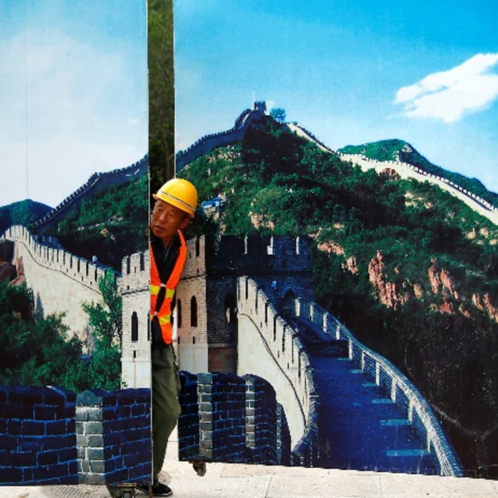 <p>A worker looks through the fence of a construction site that is decorated with pictures of the Great Wall at Badaling, north of Beijing, China, September 1, 2016. REUTERS/Thomas Peter</p>
