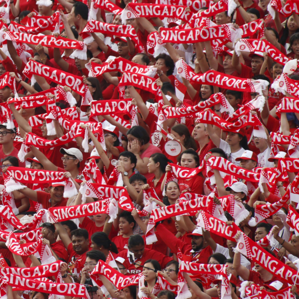 <p>People hold up Singapore banners during Singapore’s Golden Jubilee celebration parade for the nation’s 50th anniversary at Padang near the central business district on August 9, 2015.</p>
