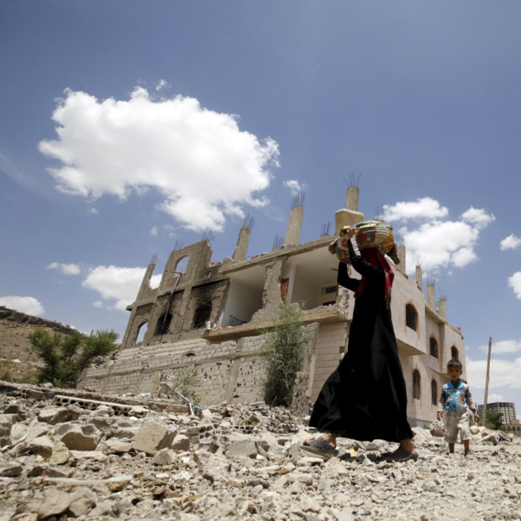 <p>A woman and a boy walk past the ruins of buildings destroyed in Saudi-led air strikes in Yemen’s capital Sanaa. September 13, 2015.</p>
