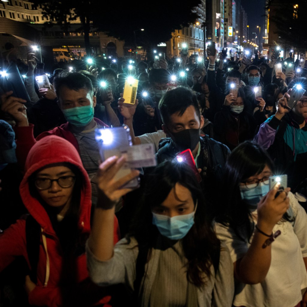 <p>Protesters raise mobile phones as they gather to show support for protesters inside the Hong Kong Polytechnic University (PolyU) campus, November 19, 2019</p>
