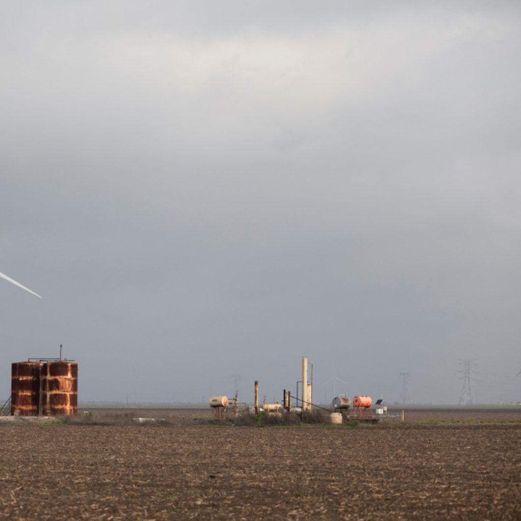 A wind turbine spins next to rusted metal structures in Gregory, Texas, U.S.