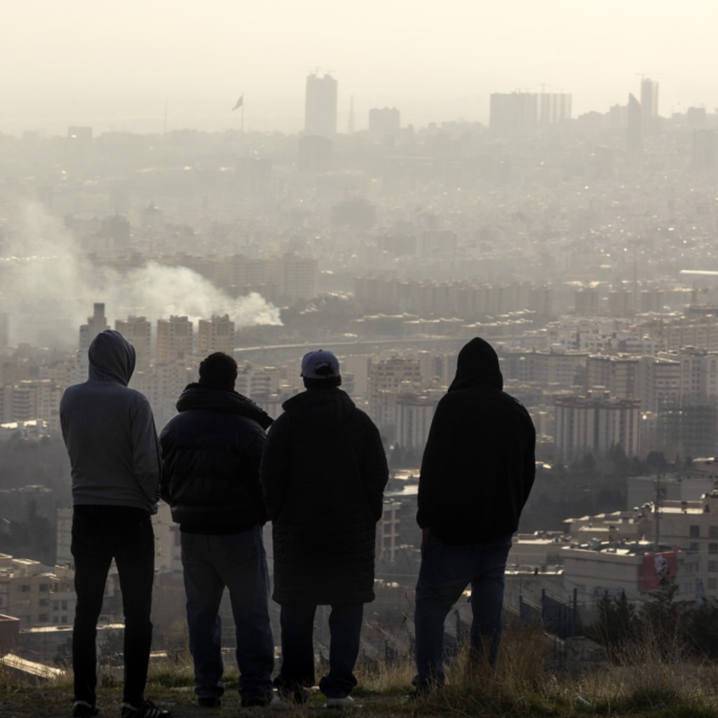 <p>Men watch from a hillside as a plume of smoke rises after an explosion on March 2, 2026 in Tehran, Iran.</p>

