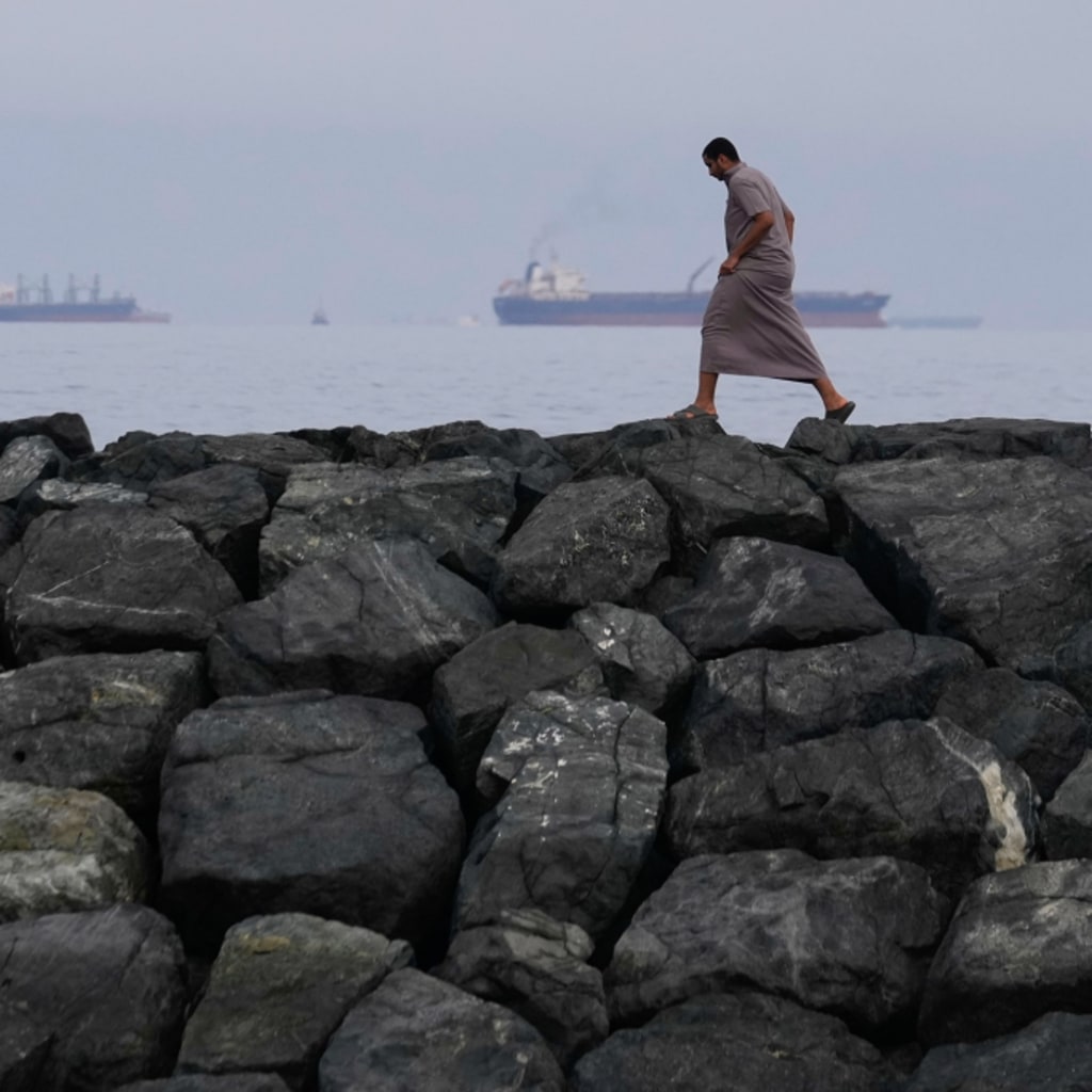<p>A man walks along the shore as oil tankers and cargo ships line up in the Strait of Hormuz, seen from Khor Fakkan, United Arab Emirates, Wednesday, March 11, 2026.</p>
