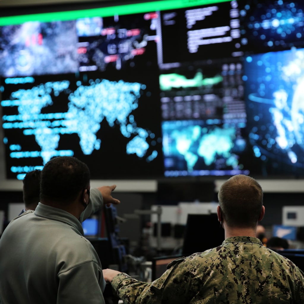 Two officials at U.S. Cyber Command, headquartered in Fort George G. Meade, Maryland, examine a row of screens at their workplace. 