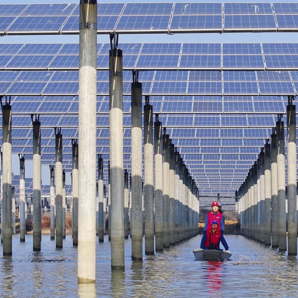 Workers check solar panels installed over a lake from underneath while in a boat.