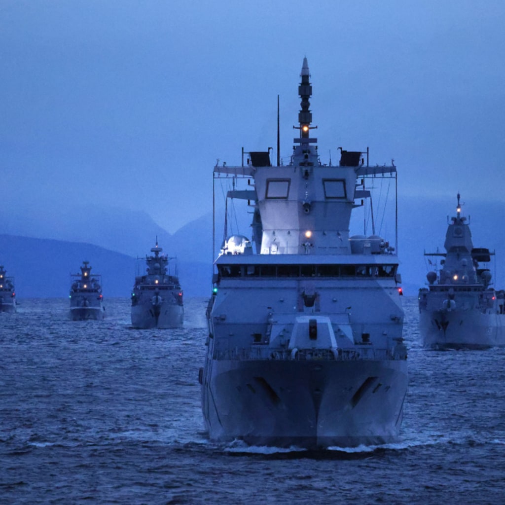 Six battleships sail on open water at twilight