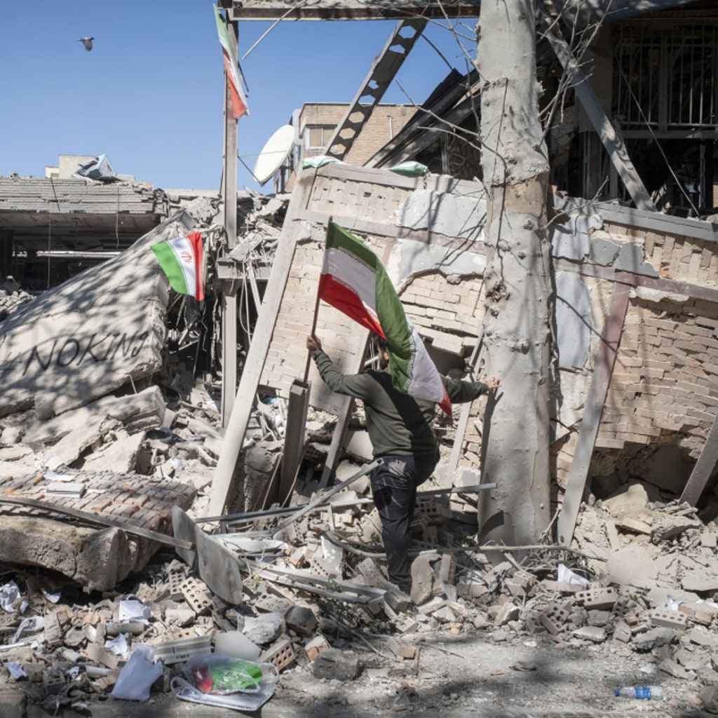 An unidentified man places a national flag on the ruins of the Sharif University of Technology's data center, which was struck on April 6 during ongoing military operations in Tehran, Iran, on April 7, 2026.