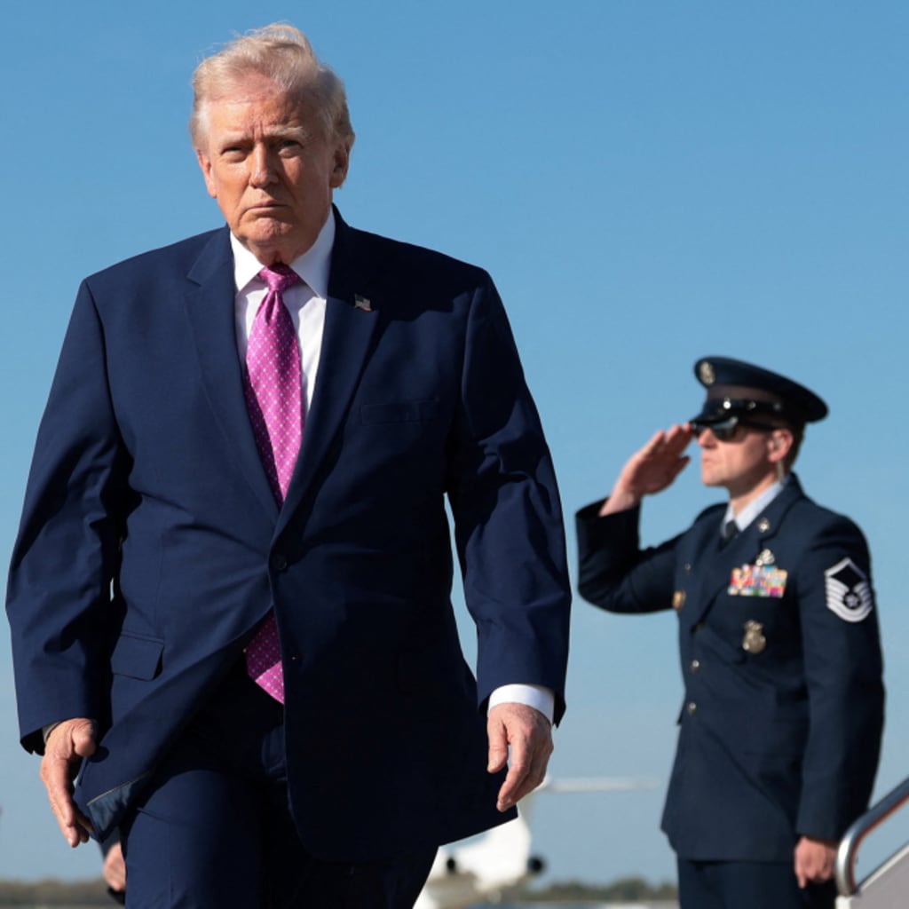 U.S. President Donald Trump walks to board Air Force One on his way to Virginia, at Joint Base Andrews in Maryland, on April 10, 2026. An officer in a blue uniform salutes behind him.