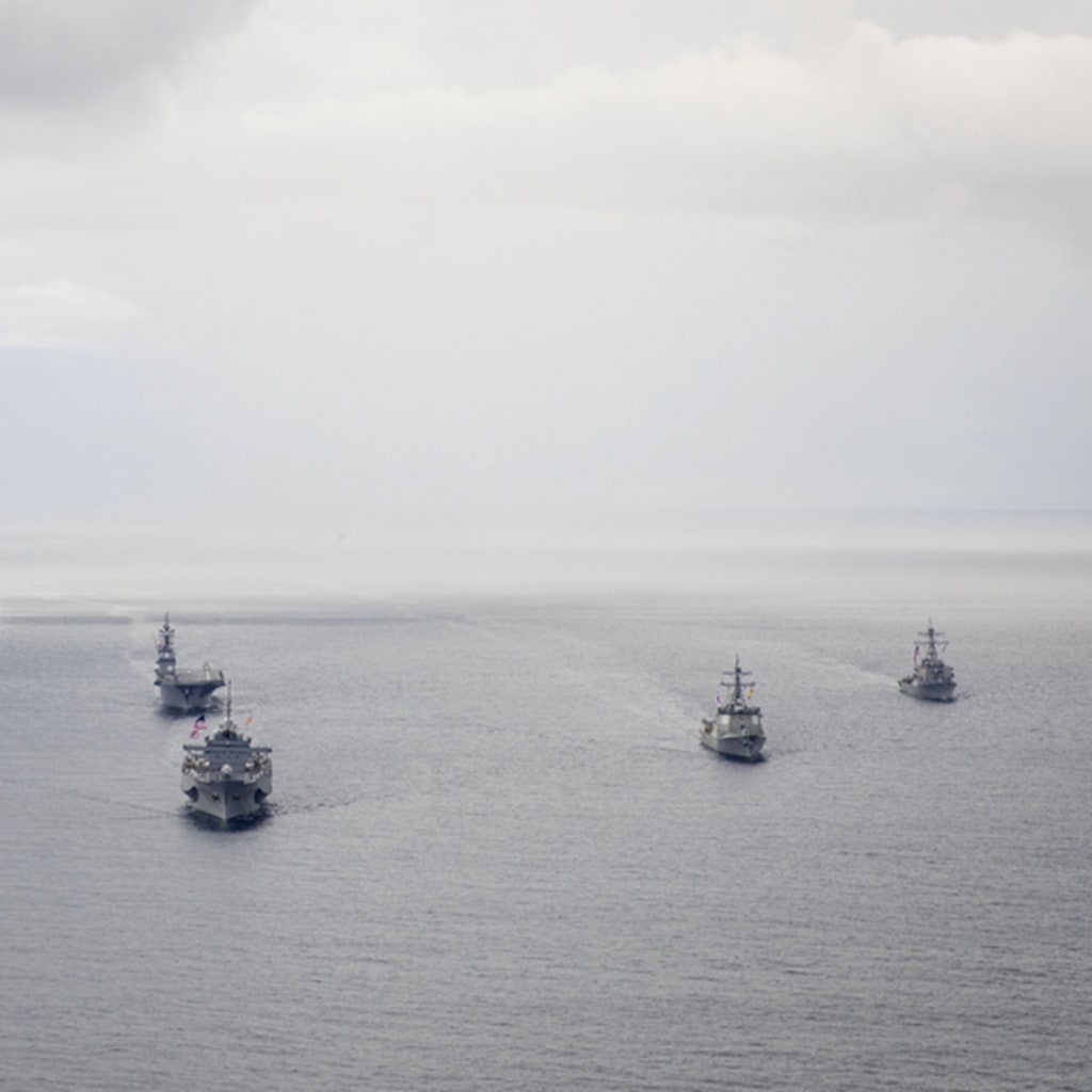 Several U.S. naval vessels cruising on open water.