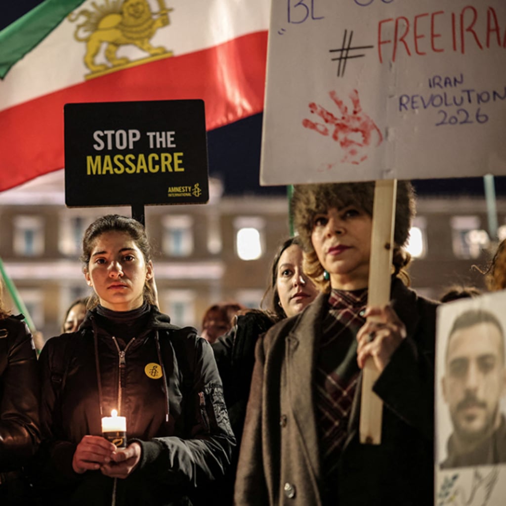 Activists stand in a line holding Iranian flags, candles, and signage to peacefully protest the Iranian crackdowns on civilian demonstrations in front of the Greek Parliamentary building.