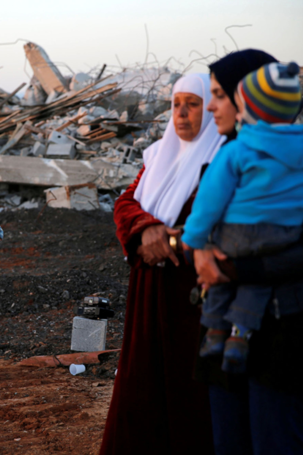 <p>Arab citizens of Israel stand near demolished houses in the northern city of Qalansawe.</p>
