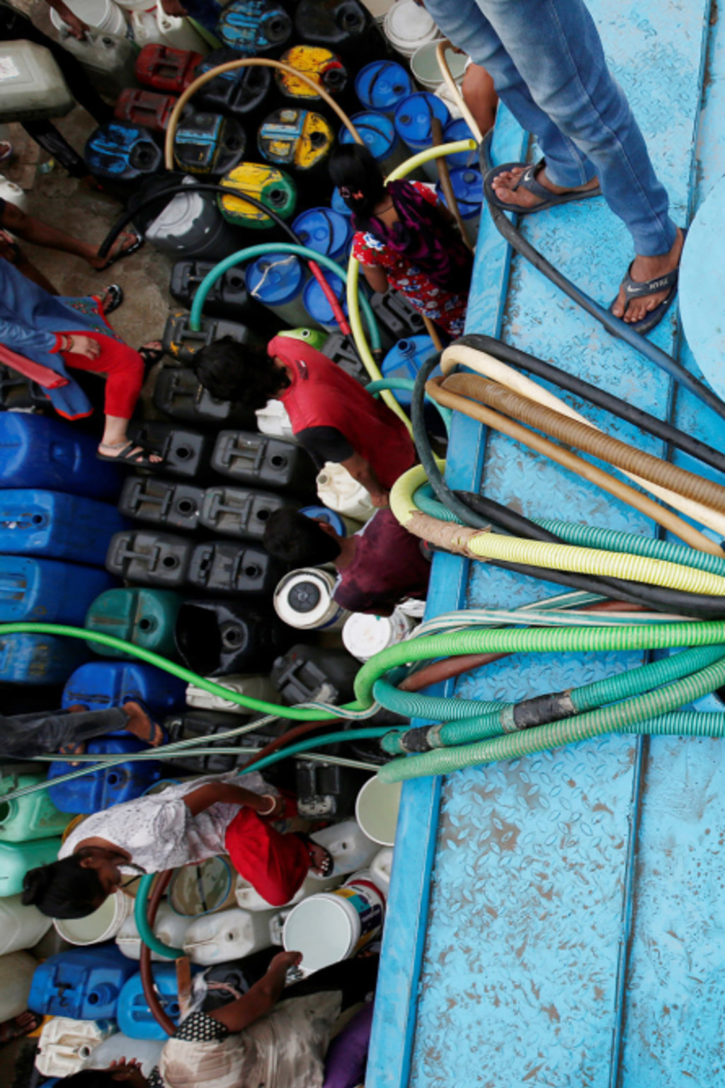 <p>New Delhi residents fill containers with drinking water from a municipal tanker in June 2018.</p>
