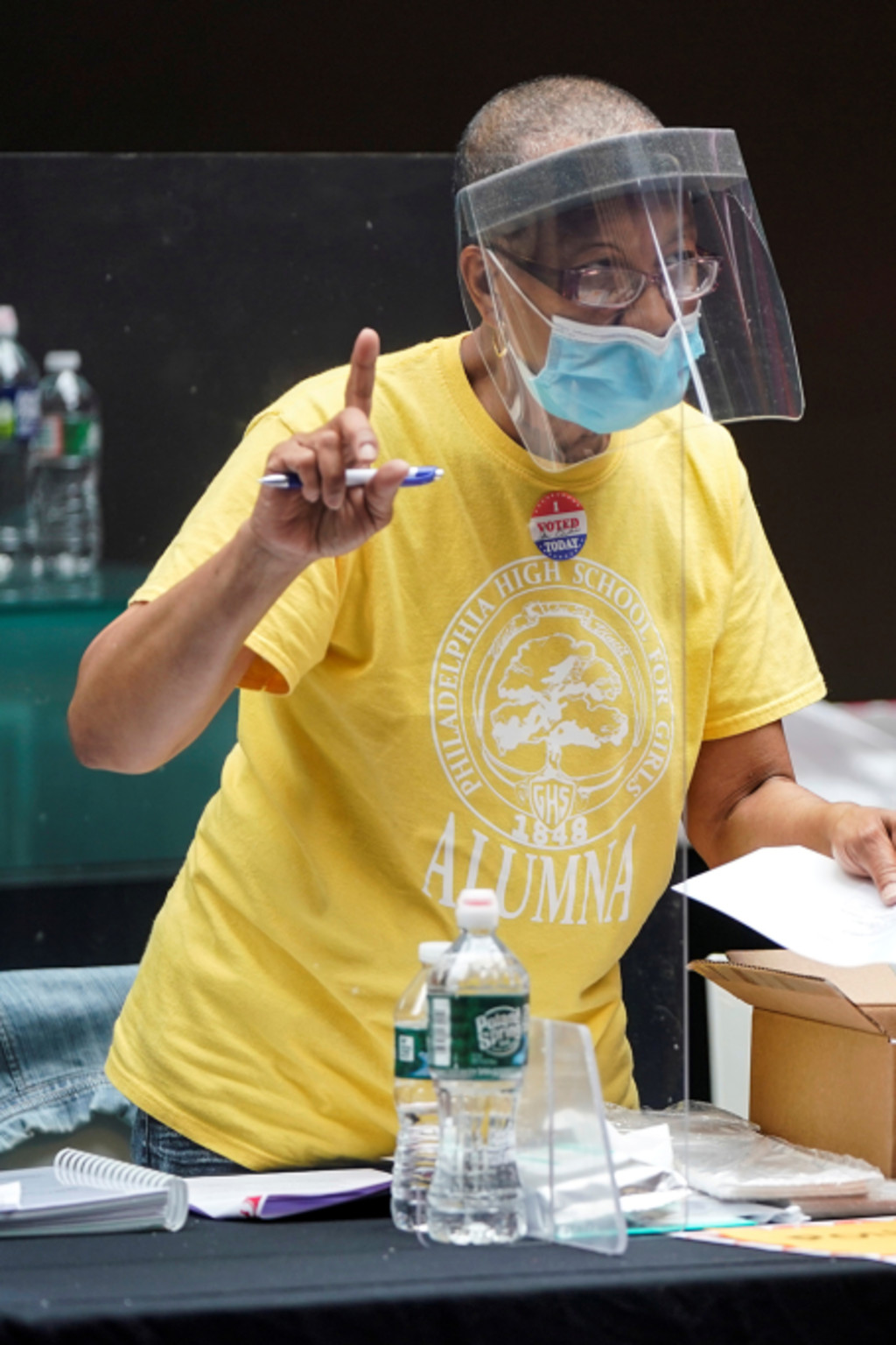 <p>A poll worker and voter wear masks to prevent the spread of COVID-19 during a U.S. primary election.</p>