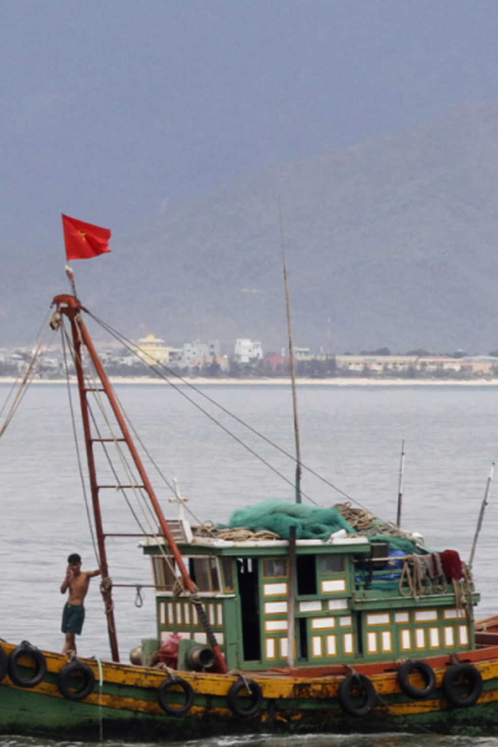 <p>A Vietnamese fishing boat goes past the USS Chung-Hoon at a port in Danang city, July 15, 2011.</p>