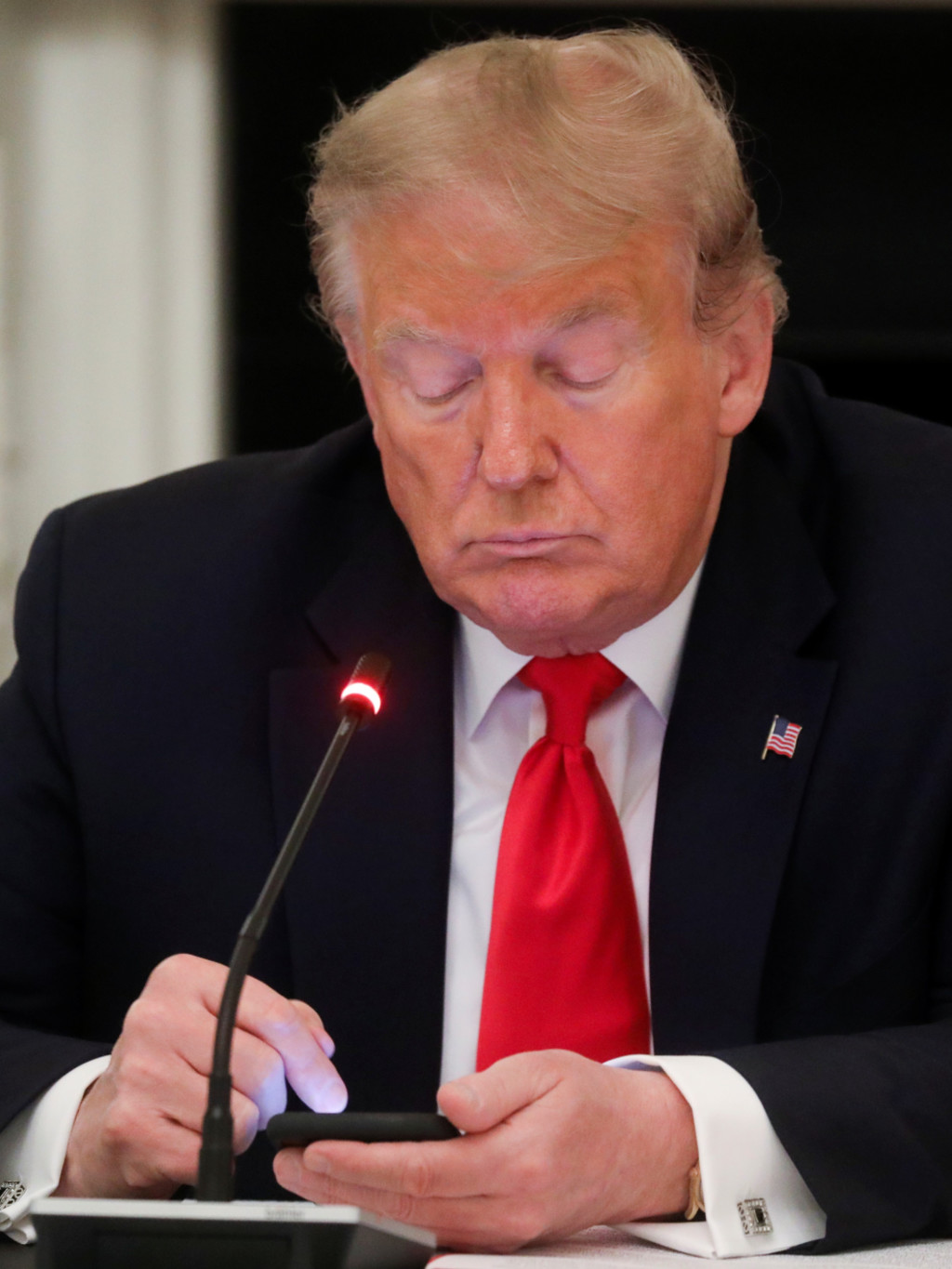 U.S. President Donald Trump taps the screen on a mobile phone at the approximate time a tweet was released from his Twitter account. 