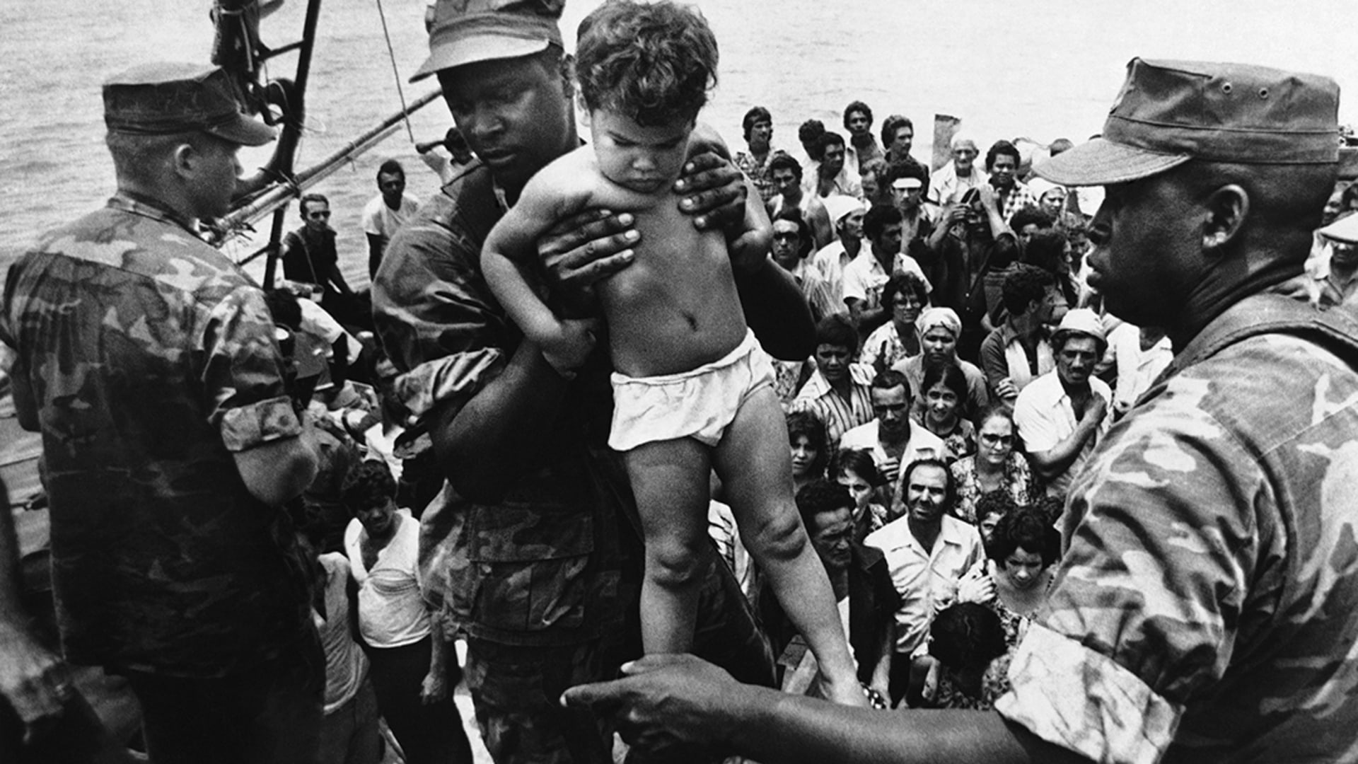 A U.S. Marine helps a child off of a Cuban refugee boat. 
